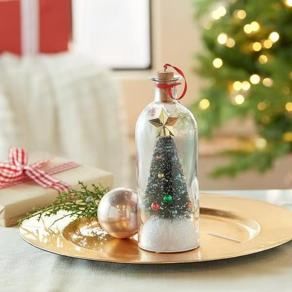 The Forever Tree bottle beside wrapped gifts, with a lit Christmas tree behind it
